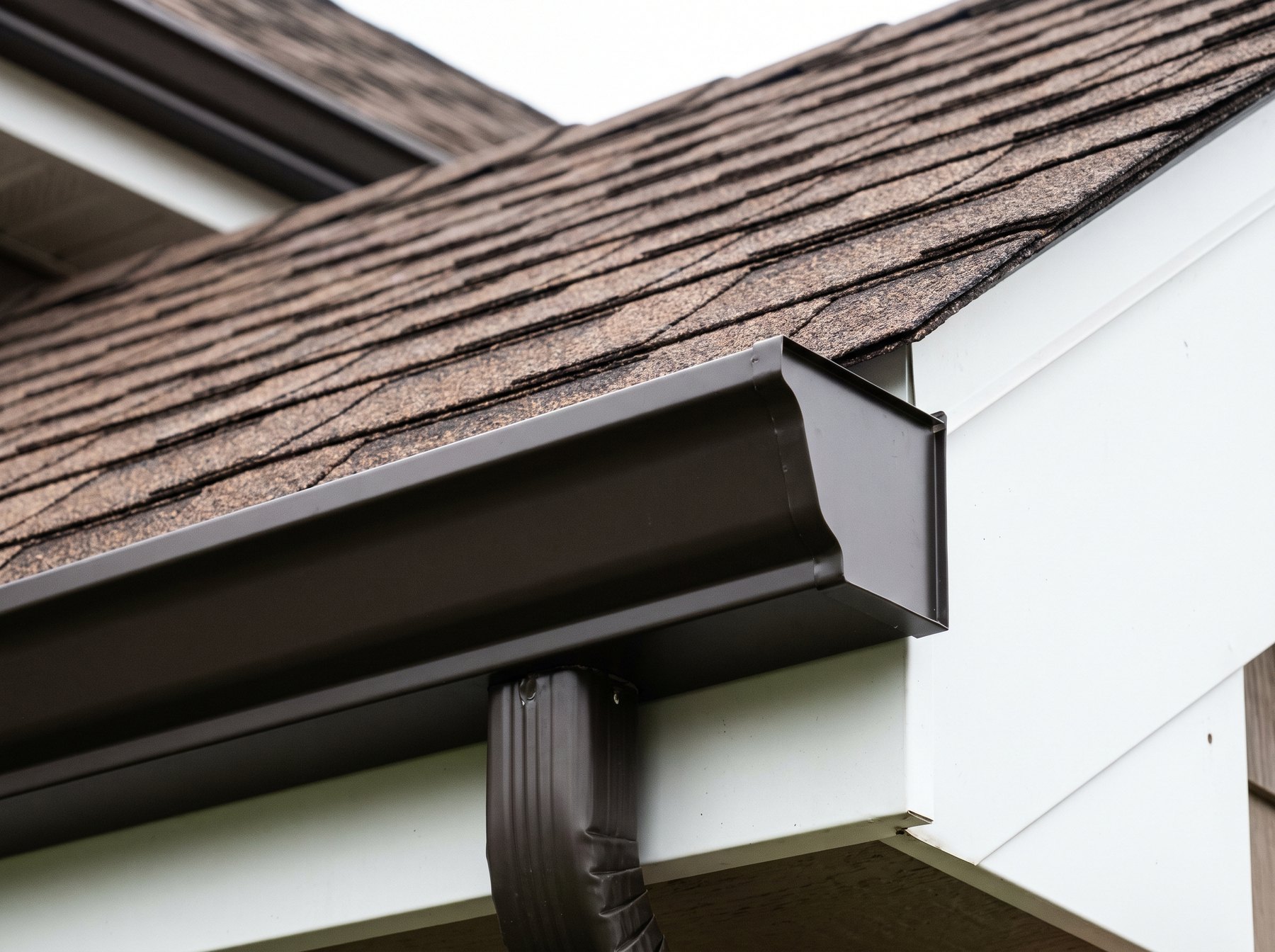 A Redbud roofer installing seamless aluminum gutter on a clean fascia
