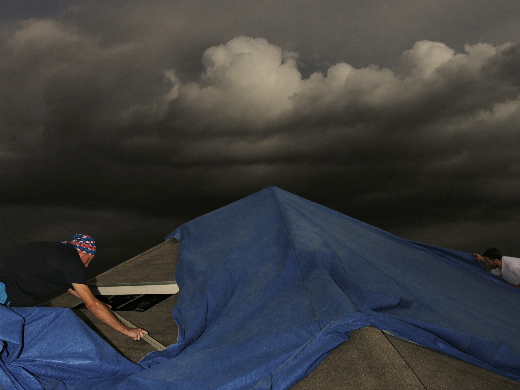 Redbud crew securing a tarp over storm damage as the clouds clear